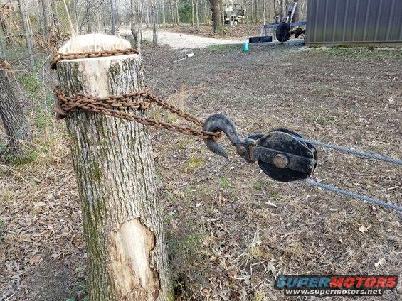 shopstump05.jpg With 2 lines, I get nearly double the force at half the speed.  So I should get up to ~24K lbf on this ~3.5' tall lever, which should be enough to rip it out of the ground.  The snatch block is an antique monster that I salvaged from a BIG crane truck abandoned in the woods, so it can easily handle this.  I'm not quite as confident about the chain, but with 2 runs, it should be OK.  It's wrapped several times around the stump & itself to keep it from shifting or sliding off, even when the stump is laid down horizontally.