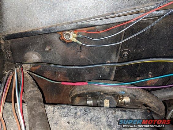 pxl_20210503_023653901.jpg The 3 grounds from C115 ground to the old voltage regulator ground.  I wire wheeled the metal bare then covered it in silicone grease to get a good connection and hopefully prevent corrosion.  The big black/yellow wire used to go to the 302's alternator and now routes over the engine to the big yellow wire at the PDB.  The green/red wire from the voltage regulator provides RUN power to the purple/orange wire going to C115 and to the green wire I added which will go to a RUN/START relay shown in a later picture.