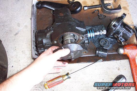 10sectorshaftremoval.jpg Remove the two bolts that hold the sector shaft in, then drive it up from the bottom.  Do NOT remove the adjusting nut like I did.  The sector shaft must be centered (gearbox centered) in order for you to remove it.