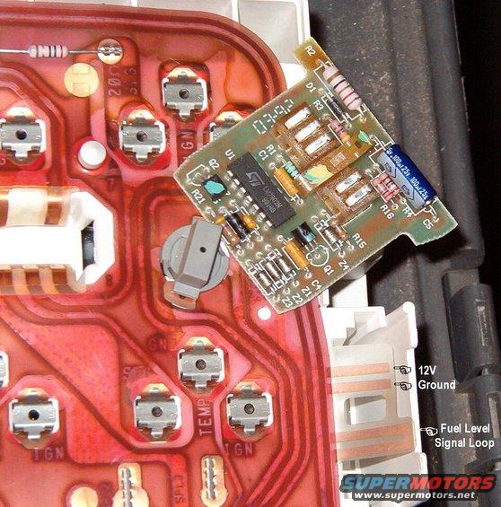04sloshslot.jpg The truck cluster is ready to have the module with only 3 modifications:
1) the sender loop, which extends past the rest of this flap, can be cut off to open the circuit into 2: an input for the module from the tank (bottom), and an output from the module to the gauge (top).  This should only be done on SINGLE-tank applications since the delay will interfere with the gauge when switching tanks; on dual-tank applications, DO NOT CUT the loop, but insulate or remove the gauge output wiper (the inboard one of the pair to the R of the catch) so the gauge has no delay (no anti-slosh);
[url=http://www.supermotors.net/vehicles/registry/media/846881][img]http://www.supermotors.net/getfile/846881/thumbnail/lowfuel88ke.jpg[/img][/url]
2) the 12V input to the module must be connected to another power circuit that is only active with the key forward in START or RUN, or back in ACC.  On '92-96 non-tach (base) clusters, the trace is already powered.
3) since the film circuit lacks a trace for the ground output to the light, and there's no unused bulb position on the cluster, an external light will have to be installed wherever it looks good to you.  The light isn't necessary for the module to work, but since truck gas tanks don't run side-to-side, they don't suffer from slosh that would affect the level gauge, so without the light, there's no reason for this mod.  Modifying the face to say &quot;Low Fuel&quot; would be difficult, but placing the light behind the fuel pump icon on the gauge face or near the &quot;E&quot; will make its meaning obvious.  With care, a hole can be drilled in the back of the gauge face to keep the light in-place, and to make it easier to see, and to isolate it from the gauge illumination.  But a bright light will shine through the gauge face without drilling.
IF THE IMAGE IS TOO SMALL, click it.

Module terminals, top-to-bottom:
Light output (ground for ON)
12V input
Ground input
Fuel level output (delayed)
Fuel sender input

On F-series with dual tanks:
This module is designed to prevent sudden changes in the needle's position while the key is in RUN.  So when switching tanks, it will take some time for the module to accept the new level & allow the gauge to display it, UNLESS the key is cycled OFF.  So to make this mod more functional, simply apply insulating tape to the module's output terminal and leave the signal loop of the film circuit intact.  This will eliminate the anti-slosh feature, but still allow the low fuel light to work.

See the PREVious & NEXT several captions...