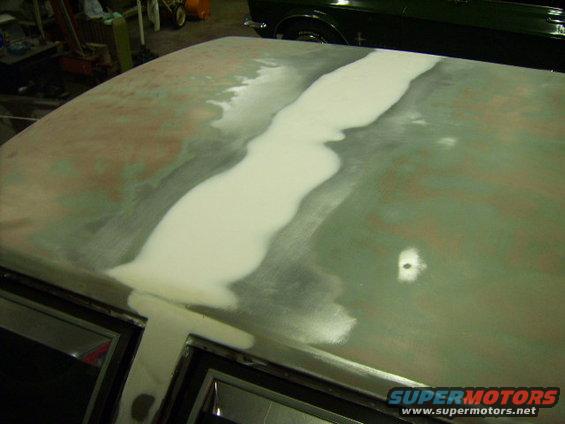 dsci1129.jpg What I thought was close to finished.  I fixed the small dent in the lower right of this picture.   I sprayed the center with primer and it became apparent that a ton more filler needed sanded out.  The "pattern" in the middle of the roof eventually was spread out over the entire bondo patch.