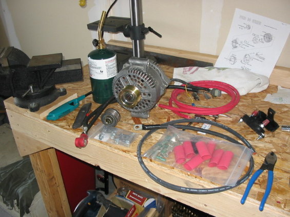 115_1529.jpg lots of stuff....200A large case alt., black and red 2GA welding wire, rated 100 below to 221*, 600V (all this is from Fireguy on FSB.com), cable cutter, heavy duty ends with solder bullets and colorcoded heat shrink, new low amp wiring harness, 225A fuse with protective fuse block, and finally not from Fireguy... new mil spec battery connectors.  Also shown is the smaller 1 7/8" pulley.  Didn't want this as the one shown as you will in the next pic, is already a wee bit smaller than the stock 2  5/8ths pulley (the shiny one installed is 2  1/4").